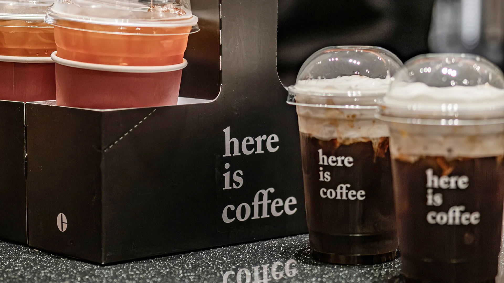 Barista se pruža da uzme poklopce za poneti u prostoru za pripremu kafe, gde su čaše, kese, salvete, slamke i nosači za pića smešteni pored espreso stanice